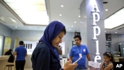 FILE - An Iranian woman tries out an iPhone in an electronics shop selling Apple products in Tehran, Iran, Aug. 5, 2015.