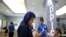 FILE - An Iranian woman tries out an iPhone in an electronics shop selling Apple products in Tehran, Iran, Aug. 5, 2015.