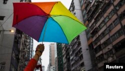 Seorang peserta memakai payung pelangi saat mengikuti parade LGBT di Hong Kong (foto: dok). 