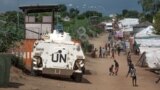 Some of the more than 30,000 Nuer civilians sheltering in a U.N. base in South Sudan's capital, Juba, for fear of targeted killings by government forces walk by an armored vehicle and a watchtower manned by Chinese peacekeepers, July 25, 2016.