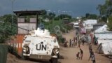 FILE - Civilians sheltering in a U.N. base in South Sudan's capital, Juba, for fear of targeted killings by government forces walk by an armored vehicle and a watchtower, July 25, 2016.