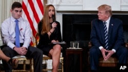 Para pelajar SMU Marjory Stoneman Douglas yang selamat dalam insiden penembakan, Jonathan Blank, dua dari kiri, dan Julia Cordover, ibu Jonathan, Melissa Blank, kiri, mendengarkan Presiden Donald Trump dalam sesi dengar pendapat di Gedung Putih, 21 Februari 2018. 