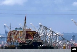 FILE - The collapsed Francis Scott Key Bridge rests on the container ship Dali, May 12, 2024, in Baltimore, as seen from Riviera Beach, Md.