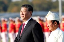 El presidente de Myanmar, Win Myint, a la derecha, y el presidente de China, Xi Jinping, inspeccionan a una guardia de honor.