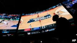 FILE - People wait in line to bet on the NCAA college basketball tournament at the Westgate Superbook sports book Thursday, March 15, 2018, in Las Vegas. (AP Photo/John Locher)