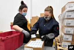 Employees with the McKesson Corporation scan a box of the Johnson & Johnson COVID-19 vaccine while filling an order at their shipping facility in Shepherdsville, Kentucky, March 1, 2021.