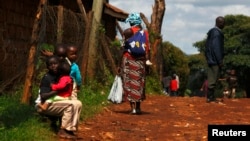 A mother carries her baby on her back in the Kangemi slum of Nairobi, Kenya on April 23, 2013.