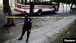 FILE - A policeman secures a crime scene after a bus driver was killed by suspected gang members during a suspension of public transport services in San Salvador, July 27, 2015.