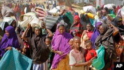 FILE - People fleeing from drought in the Lower and Middle Shabelle regions of Somalia carry their belongings as they reach a makeshift camp for displaced persons in the Daynile neighborhood on the outskirts of the capital Mogadishu, May 18, 2019.