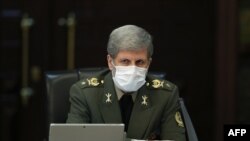 A handout picture provided by the Iranian presidency on March 11, 2020 shows Iranian Defense Minister Brigadier General Amir Hatami wearing a protective mask and gloves during a cabinet meeting in the capital Tehran.