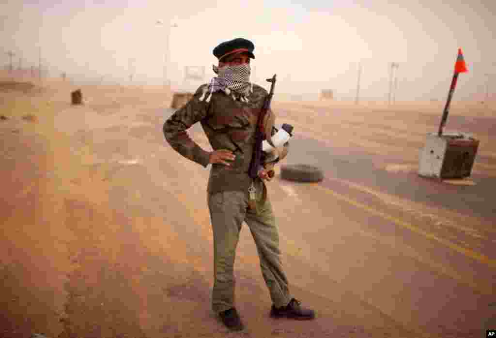 May 11: A rebel soldier stands guard at a windswept check point on the outskirts of Benghazi, Libya. (AP Photo/Rodrigo Abd)