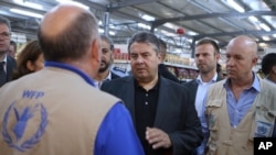 German Economy Minister Sigmar Gabriel, center, visits a supermarket at the Zaatari refugee camp near Mafraq, north of Amman, Jordan, Sept. 22, 2015.