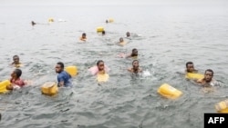 Residents swim while carrying their jerrycans as they gather to collect water amid ongoing water shortages at the shore of Lake Kivu in Goma, Jan. 29, 2025.