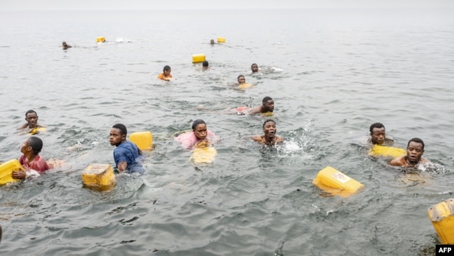 Residents swim while carrying their jerrycans as they gather to collect water amid ongoing water shortages at the shore of Lake Kivu in Goma, Jan. 29, 2025.