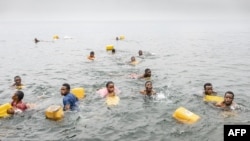 Warga berenang di Danau Kivu di Goma, Kongo, sambil membawa jeriken untuk menampung air di tengah kelangkaan pasokan air di wilayah tersebut pada 29 Januari 2025. (Foto: AFP)