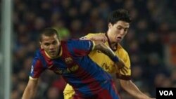 Dani Alves (kiri) beraksi ketika melawan Arsenal dalam Liga Champions. Barcelona melaju ke perempat final.