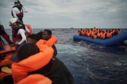 FILE - Migrants on a blue rubber boat wait to be rescued some 14 nautical miles from the coast of Libya in Mediterranean Sea, Sept. 8, 2019.