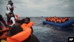 Migrants on a blue rubber boat wait to be rescued some 14 nautical miles from the coast of Libya in Mediterranean Sea, Sept. 8, 2019. 