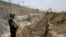 FILE - A Pakistani border guard stands on alert as an excavator digs a trench along the Pakistan-Afghanistan border at Chaman post in Pakistan, May, 16, 2014.