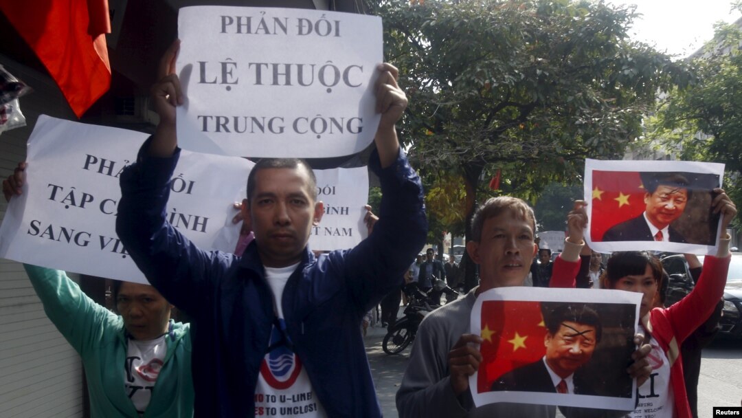Protesters hold marked images of Chinese President Xi Jinping and anti-China signs during a protest ahead of his visit to Vietnam, on the street in Hanoi, Nov. 3, 2015. 