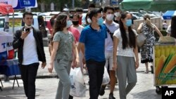Youths in face masks walk through a street market in Bishkek, Kyrgyzstan, July 24, 2020. The attorney for jailed journalist Bobomurod Abdullaey says Kyrgyzstan officials are refusing to grant access to his client due to a mandatory coronavirus quarantine.
