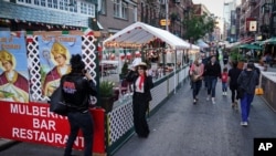 People walk through an area where restaurants operate outdoor spaces for dining that spread onto sidewalks and streets as part of continued COVID-19 economic impact mitigation efforts, Oct. 3, 2020, in New York. 