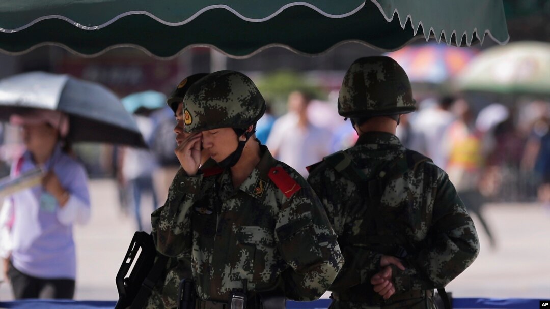 FILE - Chinese paramilitary police stand watch at a Beijing railway station, guarding against attacks by Uighur militants, Sept. 3, 2014.