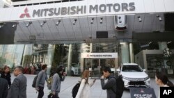 Les gens passent devant le siège de Mitsubishi Motors Corp, qui est allié à Renault-Nissan, le lundi 26 novembre 2018 à Tokyo. (Photo AP / Koji Sasahara)