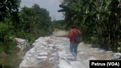 Warga melintasi jalan dari tumpukan limbah abu slag alumunium (Foto: VOA/Petrus Riski).