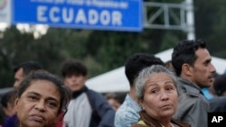 ARCHIVO - Migrantes esperan afuera de una oficina de procesamiento de inmigración en el puente de Rumichaca después de cruzar la frontera de Colombia a Rumichaca, Ecuador, el miércoles 12 de junio de 2019.