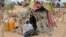 FILE - A woman is seen sitting in front of a tent in the Assaga refugee camp, set up by the U.N. for Nigerian refugees who fled to southeast Niger to escape Boko Haram militants, Sept. 16, 2015.