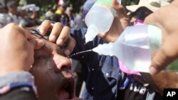 Demonstran anti pemerintah membersihkan matanya setelah polisi menembakkan gas air mata di Bangkok, Thailand, 1 Des, 2013.