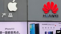 FILE - In this Thursday, March 7, 2019, file photo, logos of Apple and Huawei are displayed outside a mobile phone retail shop in Shenzhen, China's Guangdong province. Few U.S. companies are more vulnerable to a trade war with China than Apple. The…