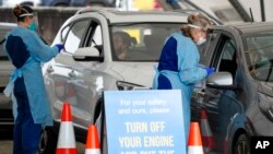 Personnel take samples for COVID-19 tests at a drive-thru testing facility set up in Bondi Beach, in Sydney, Australia, Jan. 8, 2022.