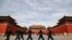 FILE - Soldiers wearing protective face masks march past the closed entrance gates to the Forbidden City, usually crowded with tourists before the coronavirus outbreak in Beijing, March 12, 2020.