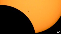 FILE - In this image made available by NASA, the International Space Station is silhouetted against the sun during a solar eclipse Monday, Aug. 21, 2017, as seen from Ross Lake, Northern Cascades National Park in Washington state. (Bill Ingalls/NASA via AP, File)