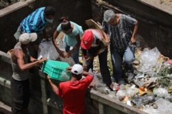 FILE - People search for food at a garbage container during the closing hour at the Coche wholesale market amid COVID-19 outbreak in Caracas, Venezuela, July 31, 2020.