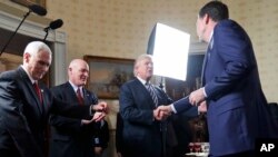 FILE - Vice President Mike Pence, left, and Secret Service Director Joseph Clancy stand as President Donald Trump shakes hands with FBI Director James Comey during a reception for inaugural law enforcement officers and first responders Jan. 22, 2017.