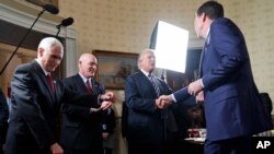FILE - Vice President Mike Pence, left, and Secret Service Director Joseph Clancy stand as President Donald Trump shakes hands with FBI Director James Comey during a reception for inaugural law enforcement officers and first responders in the Blue Room of