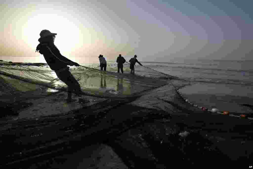 Palestinian fishermen pull in their nets from the waters of the Mediterranean Sea during sunset at the beach in Gaza City.&nbsp; 