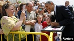 U.S. President Barack Obama signs a framed portrait of himself for 16-year-old Myra Soukup upon his arrival in Minneapolis, June 1, 2012. 