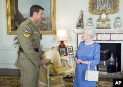 FILE - Britain's Queen Elizabeth II greets Corp. Ben Robert-Smith, from Australia, who was recently awarded the Victoria Cross, during an audience at Buckingham Palace in London, Nov.15, 2011.