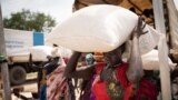 Women from Murle ethnic group carry bags of sorghum during a food distribution by United Nations World Food Program in Gumuruk, South Sudan, June 10, 2021.