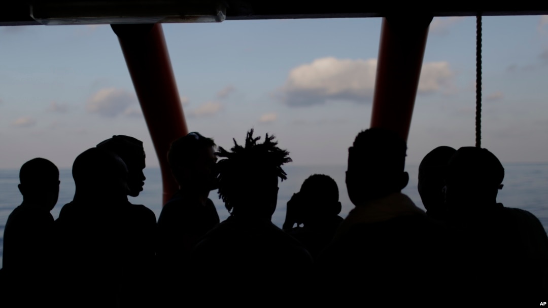 Rescued migrants are silhouetted as they look out at the horizon aboard the Ocean Viking, in the Mediterranean Sea, Sept. 13, 2019.