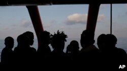 Rescued migrants are silhouetted as they look out at the horizon aboard the Ocean Viking, in the Mediterranean Sea, Sept. 13, 2019.