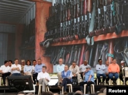 Colombia's President Juan Manuel Santos, front left, top commander of the Revolutionary Armed Forces of Colombia, FARC, Rodrigo Londono, also known as Timoleón Jiménez or Timochenko, front right, and Jean Arnault, U.N. representative for the Colombian peace process, center, watch the disarmament process in Buenavista, June, 27, 2017.