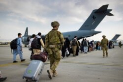 Australian citizens and visa holders prepare to board the Royal Australian Air Force C-17A Globemaster III aircraft, as Australian Army infantry personnel provide security and assist with cargo, at Hamid Karzai International Airport in Kabul