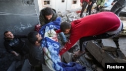 Palestinians carry the dead body of a child, at the site of an Israeli strike on a house in Nuseirat, in the central Gaza Strip, Jan. 9, 2025, amid the ongoing conflict between Israel and Hamas.