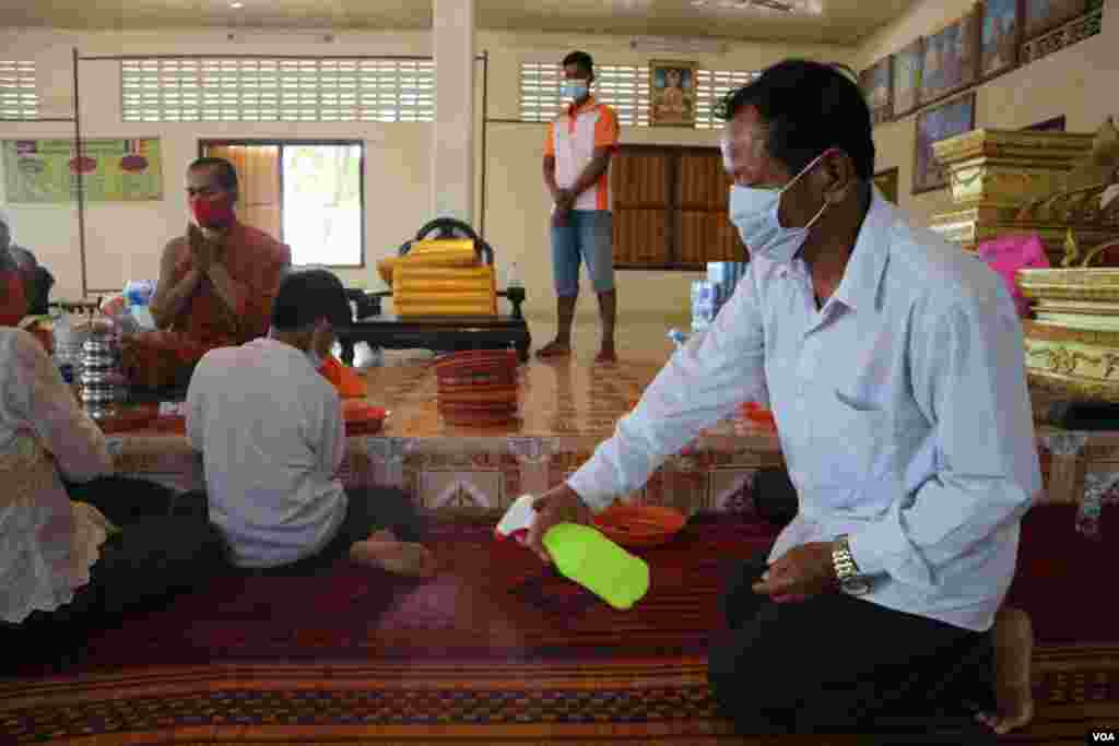 A man sprays disinfecting alcohol sanitizer on a mat in Niroth Rangsey pagoda, Phnom Penh, Cambodia, Tuesday, April 14, 2020. (Kann Vicheika/VOA Khmer)