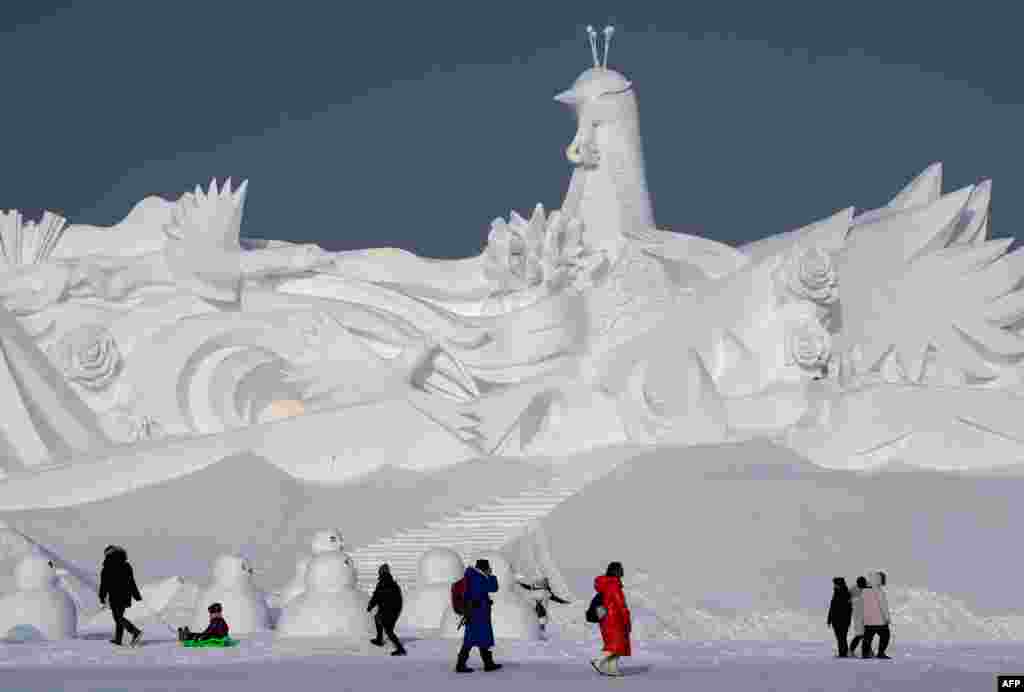 Tourists walk in front of an ice sculpture ahead of the opening of the Harbin International Snow and Sculpture Festival in Harbin, in China&#39;s northeast Heilongjiang province, Jan. 4, 2020.